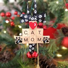 a cat mom cross ornament hanging from a christmas tree with ornaments around it