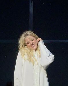 a woman is smiling while standing on stage