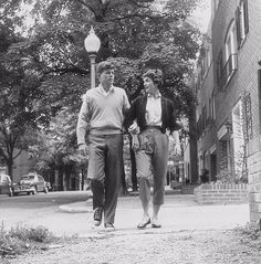 an old photo of two people walking down the street