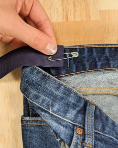 a person is opening the back pocket of their jeans with a pair of scissors in it