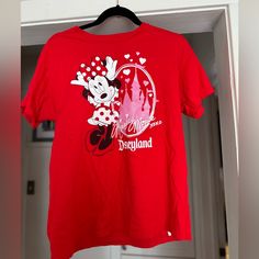 a red tshirt with minnie mouse on it hanging from a closet door in front of a white door