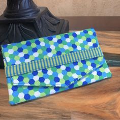 a blue and green purse sitting on top of a wooden table