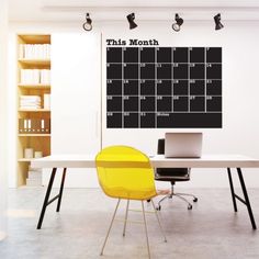 a desk with a yellow chair in front of it and a calendar on the wall