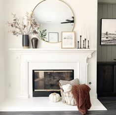 a living room with a fireplace, mirror and pictures on the mantle