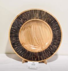 a wooden plate sitting on top of a white table next to a black and gold plate