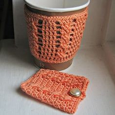 an orange crocheted cup cozying next to a coffee cup holder with a button