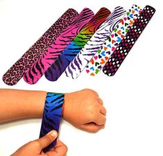 two hands holding different colored wristbands in front of each other with designs on them