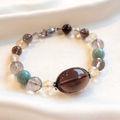 This elegant quartz and jade bracelet is the perfect addition to your jewelry collection. Crafted with natural smoky quartz, citrines and green jade. Mint Green Jade (10mm) Smoky Quartz (23x16mm) Citrines (8mm) Sterling Silver (925) Length: 8" Elegant Jade Crystal Bracelet With Gemstone Beads, Elegant Quartz Jewelry With Gemstone Beads, Brown Smoky Quartz Jewelry With Natural Stones, Elegant Quartz Round Beads Jewelry, Elegant Quartz Beaded Jewelry, Elegant Green Agate Crystal Bracelet, Elegant Agate Gemstone Bracelets, Elegant Agate Crystal Bracelet With Gemstone Beads, Elegant Brown Agate Bracelets