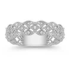 a white gold ring with diamonds on the sides and an intricate design in the middle