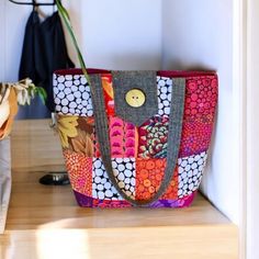 a multicolored bag sitting on top of a wooden table next to a plant