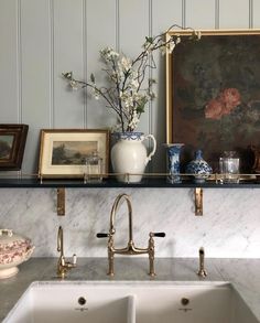 a kitchen with two sinks and framed pictures on the wall above it, along with other decor items