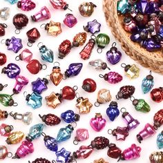 a basket filled with lots of different colored glass christmas ornament ornaments on top of a white surface