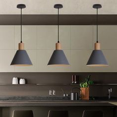 three lights hanging over a kitchen counter with bar stools