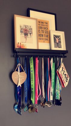 an assortment of medals hanging on a wall next to pictures and framed photos with ribbons