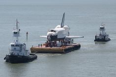 the space shuttle is being transported by tug boats