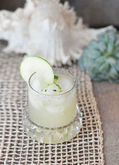 a glass filled with ice and cucumber on top of a burlly cloth