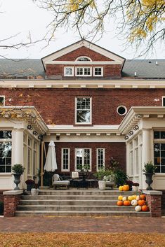 a large brick house with white trim and lots of pumpkins on the front steps