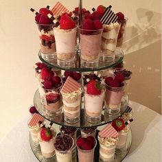 there are many desserts on the tiered plate and one is filled with strawberries