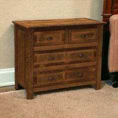 a wooden dresser sitting next to a chair in a room with carpeted flooring