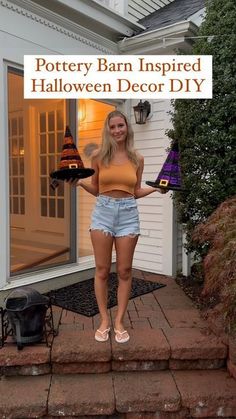 a woman is standing on steps holding two witches hats and a sign that says pottery barn inspired halloween decor diy