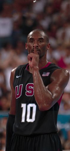 a basketball player holding his hand to his mouth while standing in front of an audience