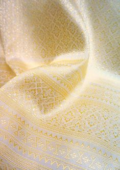 a close up view of a yellow and white fabric with an intricate design on it