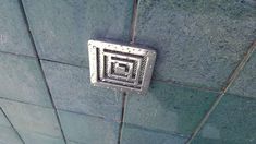 a square metal grate mounted to the side of a wall