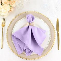 a place setting with purple napkins and silverware