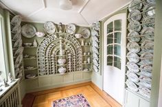 a room filled with lots of plates and glassware on the wall next to a doorway