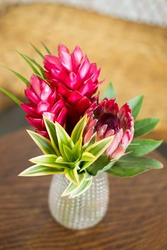 a glass vase filled with flowers on top of a wooden table