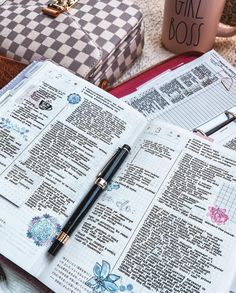 an open bible with a pen on top of it next to a cup of coffee