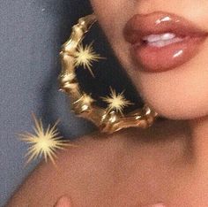 a close up of a woman's face with gold stars on her ear