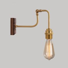 an old fashioned wall light with a bulb attached to the arm and a wooden frame