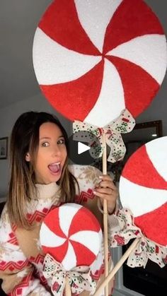 a woman holding two large lollipops in her hands and making a funny face