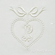 a white heart with a monogrammed letter and bow on the side, embroidered onto it