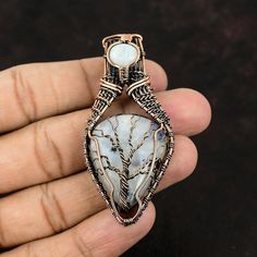 Note : Due to the natural formation of this gemstone. Slight variation in design and color are to be expected. Tree Of Life Moonstone Pendant Copper Wire Wrapped Pendant Copper Moonstone Jewelry Handmade Pendant Gemstone Copper Jewelry Gift For Mother Handmade Copper Pendant SKU : VFWP-21 Gemstone : Rainbow Moonstone Stone Shape : Oval, Pear Metal Purity : Copper Pendant Length : 70 MM Pendant Width : 30 MM A natural Moonstone opens the Heart Chakra in the human body that helps increase the psyc Nature-inspired Moonstone Jewelry With Natural Stones, Nature-inspired Moonstone Pendant Jewelry, Nature-inspired Moonstone Jewelry Gift, Unique Handmade Moonstone Crystal Necklace, Handmade Unique Moonstone Crystal Necklace, Nature-inspired Moonstone Jewelry For Healing, Unique Moonstone Crystal Necklaces For Gifts, Healing Nature-inspired Moonstone Jewelry, Unique Moonstone Crystal Necklace With Natural Stones