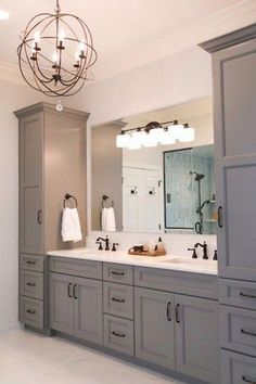 a large bathroom with two sinks and gray cabinets