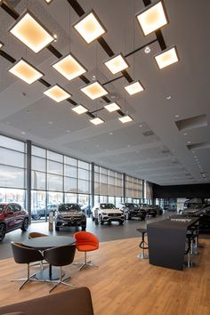 a car showroom filled with lots of cars and tables in front of large windows