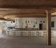 an empty bar with stools and bottles on the counter in front of large windows