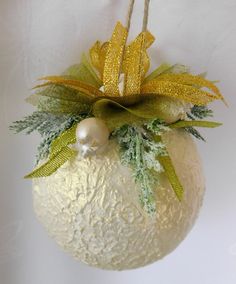 an ornament hanging on a wall with some green and yellow ribbons around it