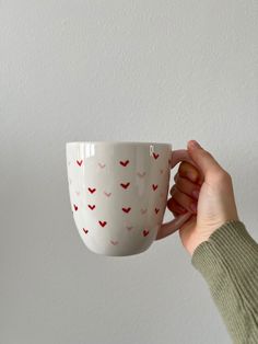 a person holding a coffee cup in their right hand with hearts painted on the side