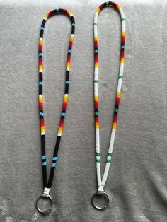 two lanyards with colorful beads are on a gray surface and one has a pair of scissors