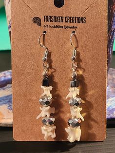 "Hand Beaded Snake Vertebrae Earrings These earrings are hand beaded with reflective silver & hematite beads, as well as actual snake vertebrae of three different sizes that are ethically sourced. They make the perfect gift for the person who seems to have everything or even yourself!  Earring dimensions: 2.25\" x .5\" Weight: .125 oz Forsaken Creations was founded in early 2023 with a passion for upcycling broken and vintage jewelry, namely rosaries, in various alternative style fashions. All items are hand crafted/altered by me in order to make the most interestingly different, fashionable pieces one can fathom. I can guarantee each piece is one of a kind and you will find nothing like it anywhere else. All natural items such as bones used in this high art jewelry have been ethically sou Snake Vertebrae Jewelry, Goth Fairycore, Bone Crafts, Bone Horn, Hematite Beads, Pastel Goth, Hand Beading, Alternative Fashion, Hippie Boho