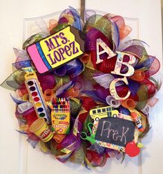 a colorful wreath with school supplies and letters hanging on the front door to welcome students