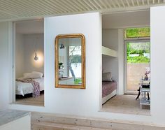 there is a bedroom with white walls and wood flooring in the room, along with a mirror on the wall