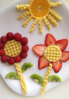 a plate with waffles, strawberries and kiwi slices in the shape of flowers