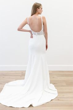 the back of a woman in a white wedding dress, standing on a wooden floor