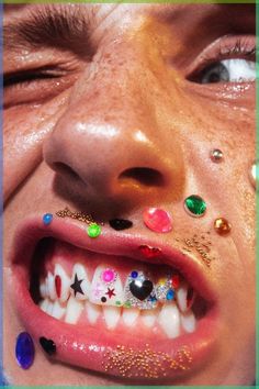 a close up of a person's face with different colored jewels on their teeth