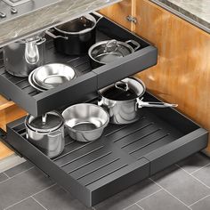 an open drawer with pots and pans on it in the middle of a kitchen