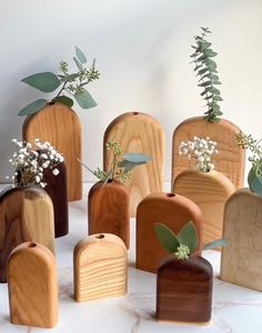 several wooden vases with plants in them on a white countertop next to each other